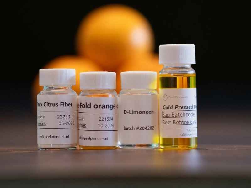 Orange peel waste next to the oils, orange cubes and citrus fibre created from it by Peel Pioneers | Waste Alchemists