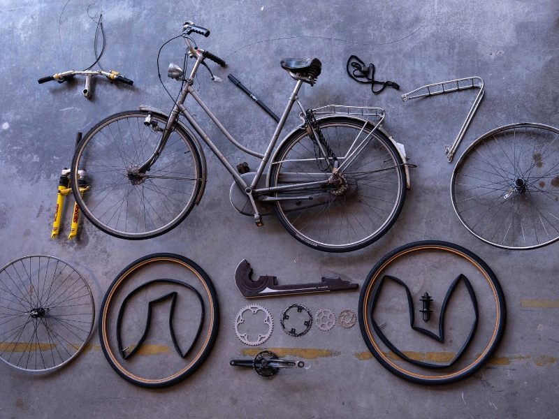 Broken bicycle parts before upcycling and the finished Roestug bike and accessories after.