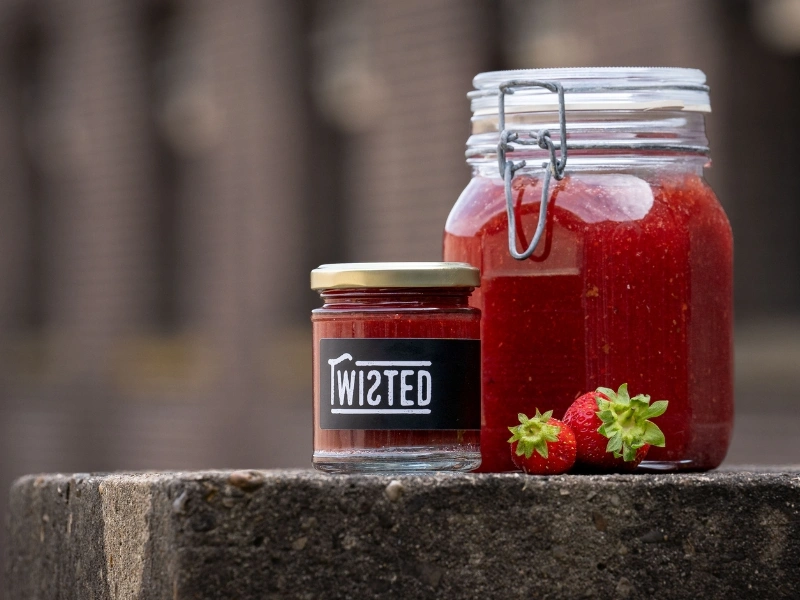 The slider reveals the core of Twisted Jams’ work. Fruits and vegetables that are too ripe, too crooked or too abundant become high-quality preserves instead of ending up in waste streams.