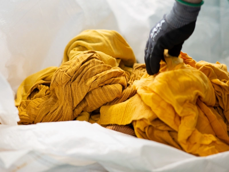 Pile of discarded corporate uniforms and textile waste before processing at i-did | Waste Alchemists